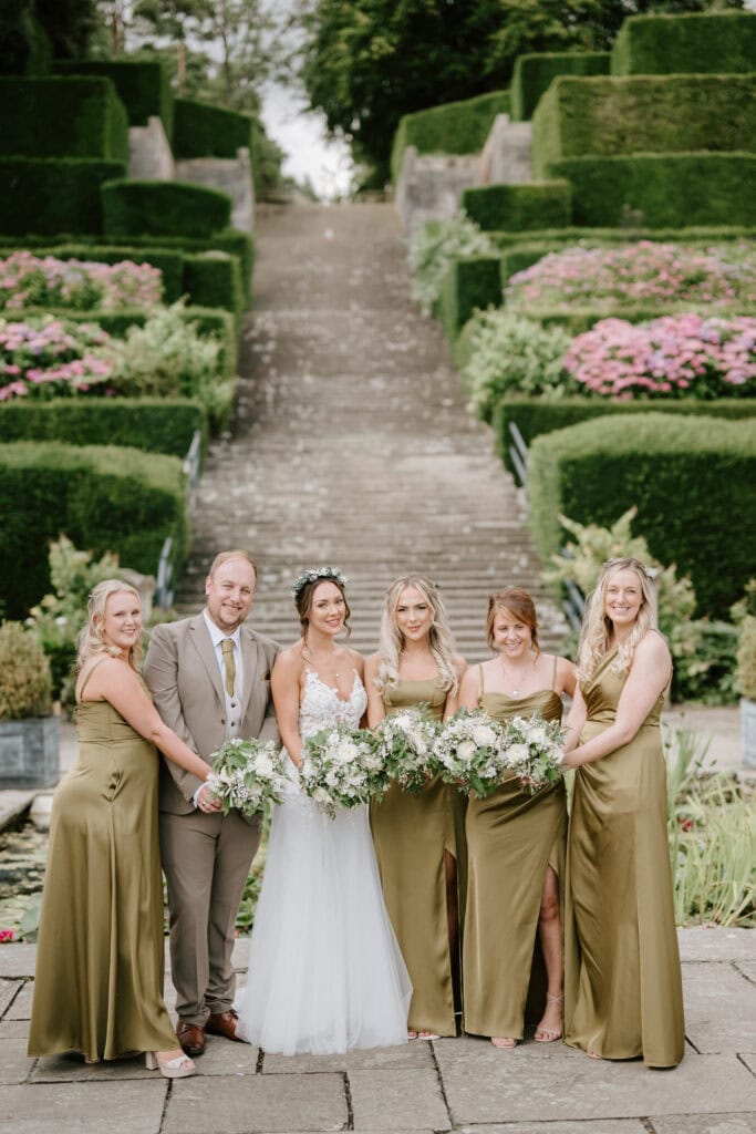 Wedding party in garden with floral bouquets.