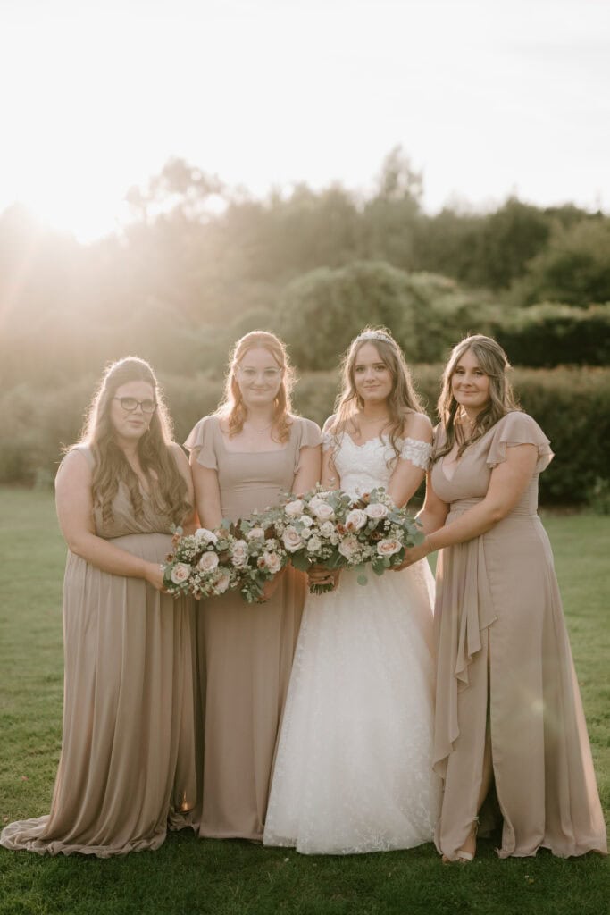 Bridesmaids and bride holding bouquets outdoors.