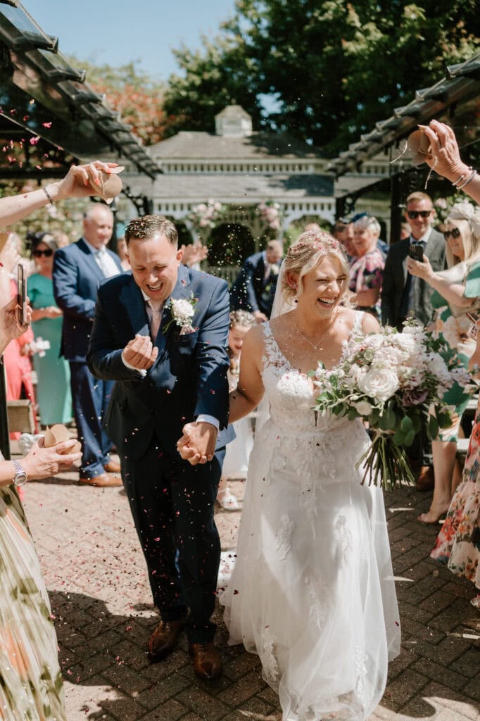 Bride and groom walking under confetti shower.