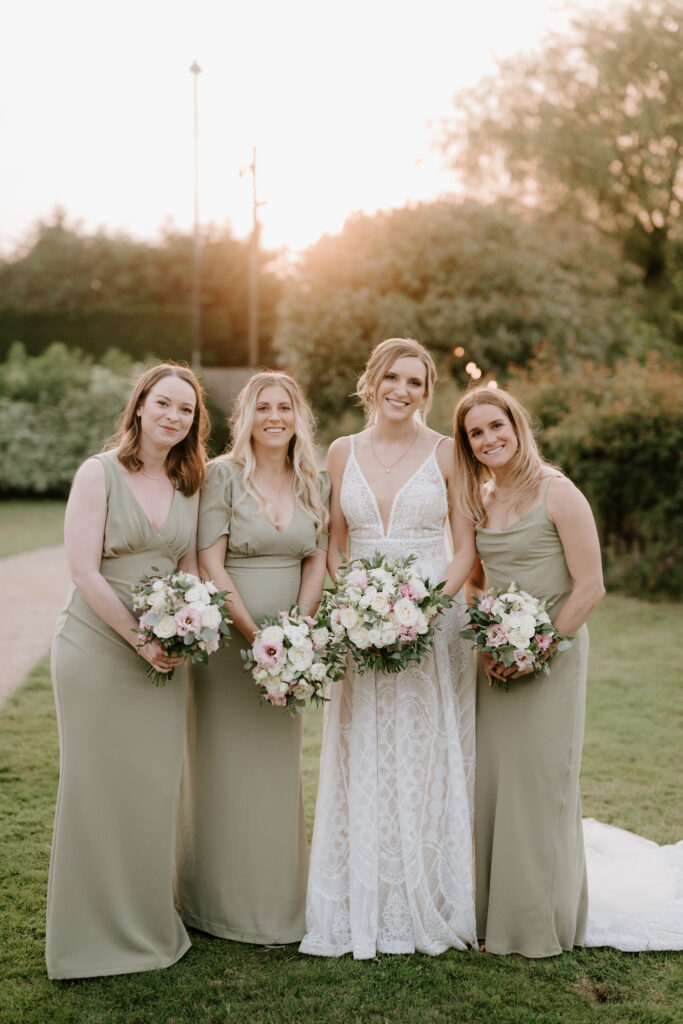 Bride and bridesmaids with bouquets in garden