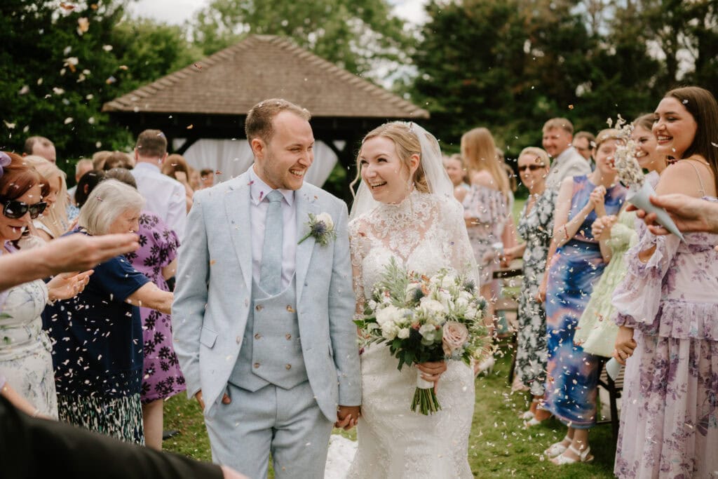 Joyful wedding couple surrounded by friends outdoors.
