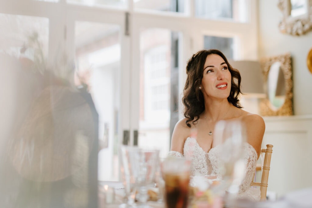 Smiling woman in white dress at indoor event.