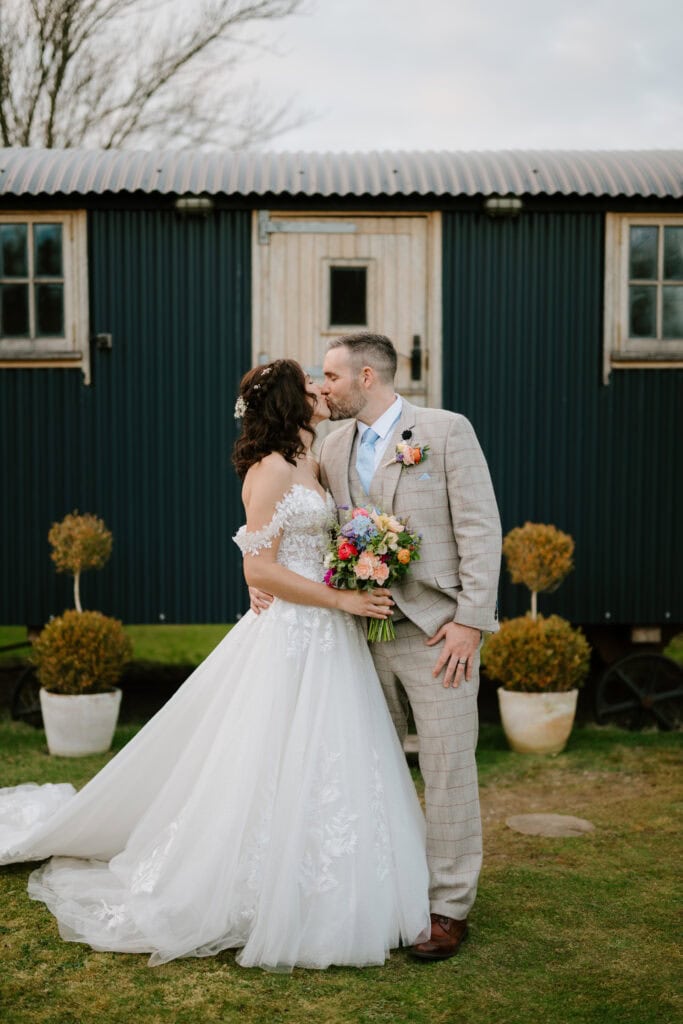 Bride and groom kissing in front of cottage.