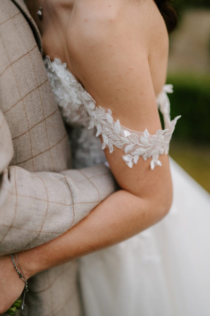 Close-up of couple hugging, wedding attire visible.