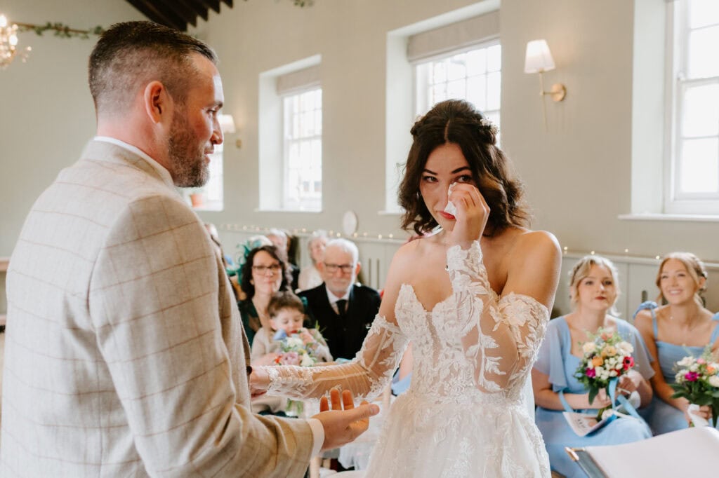 Bride tearfully exchanging vows during wedding ceremony.