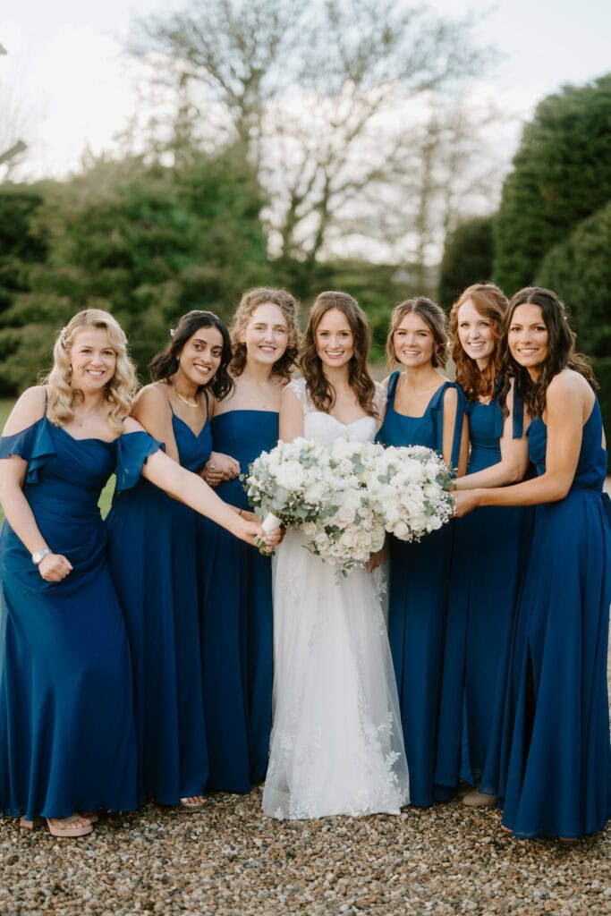 Bride with bridesmaids in blue dresses outdoors.
