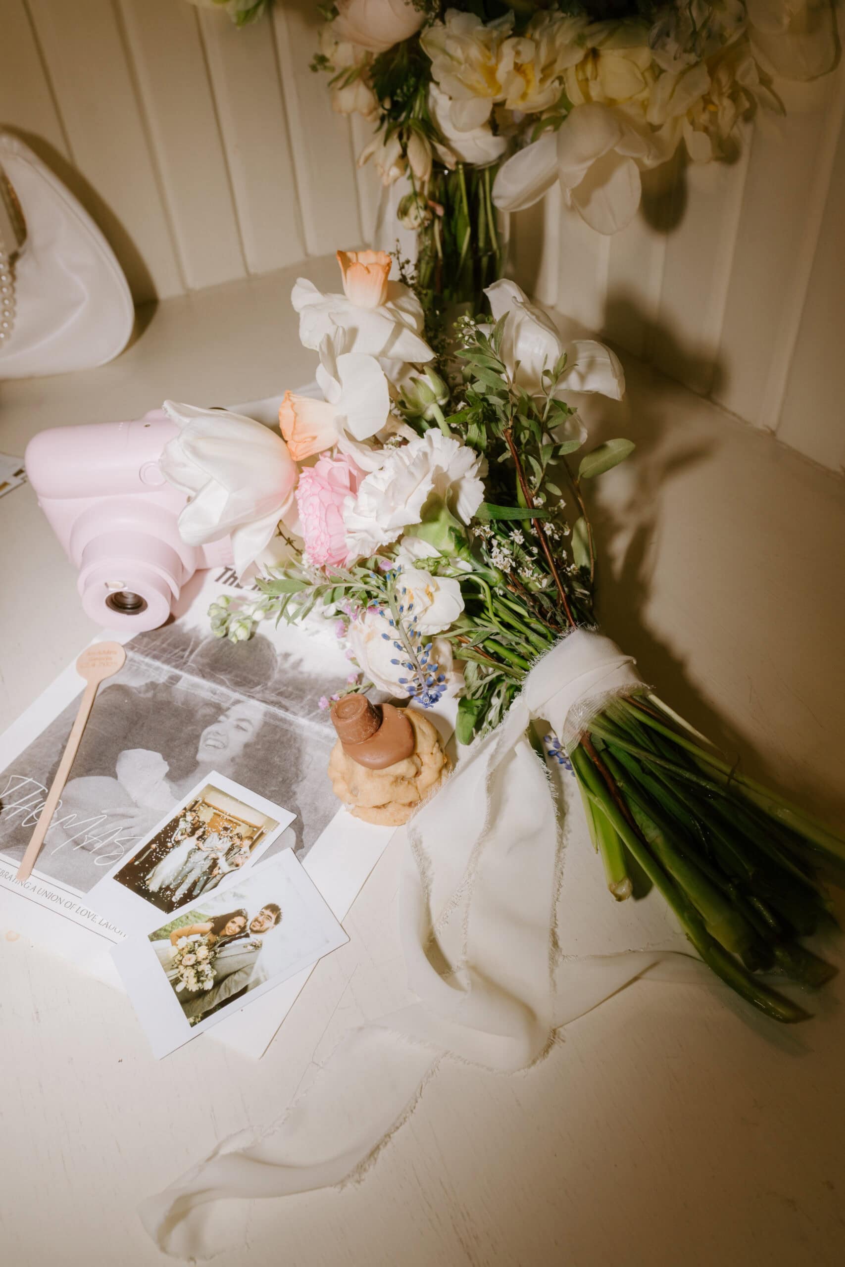 Bouquet, photos, and pink camera on table