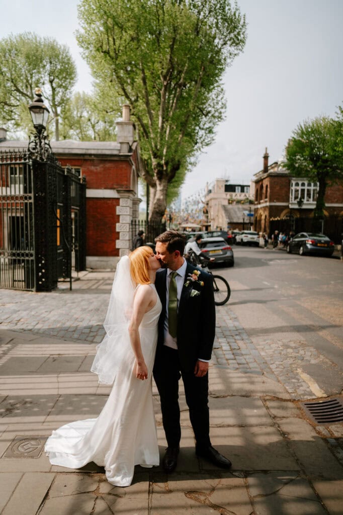 Bride and groom kiss on london city street at the trafalgar tavern