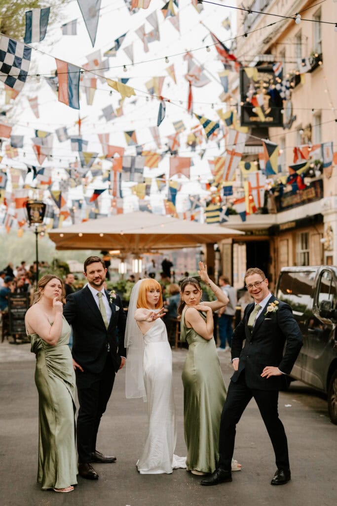 Wedding party posing under colourful flags.