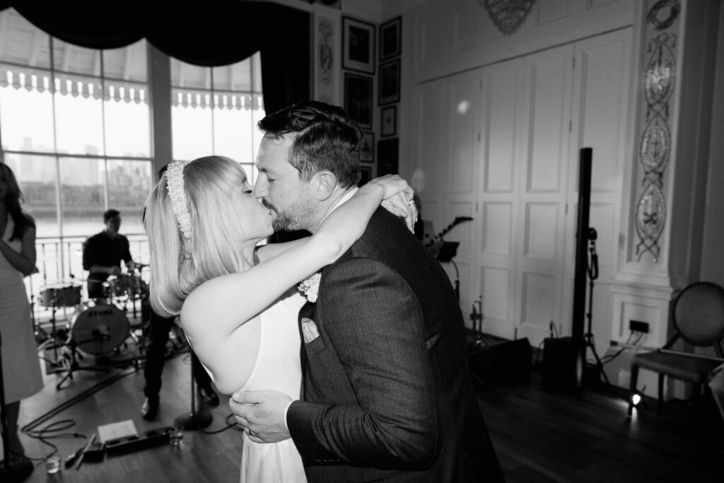 Couple kissing during wedding dance in elegant venue.