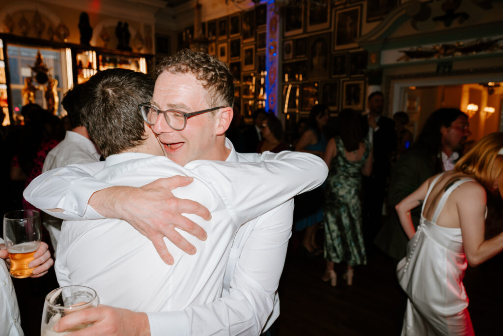 Two men hugging at a lively indoor event.