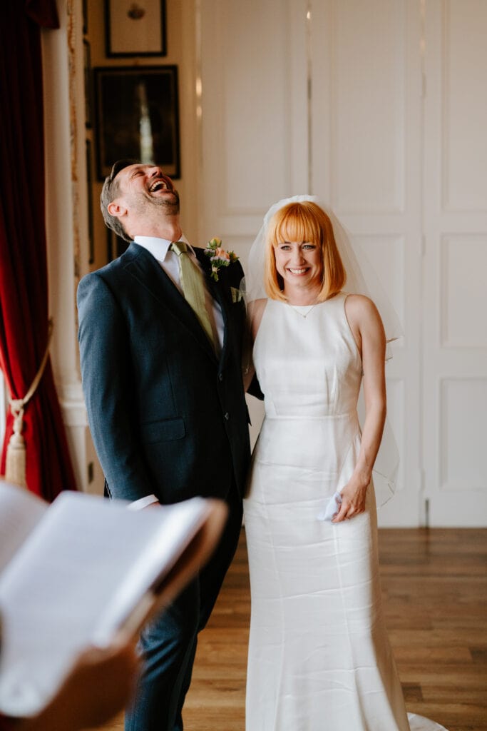 Bride and groom laughing during london wedding ceremony at the trafalgar tavern