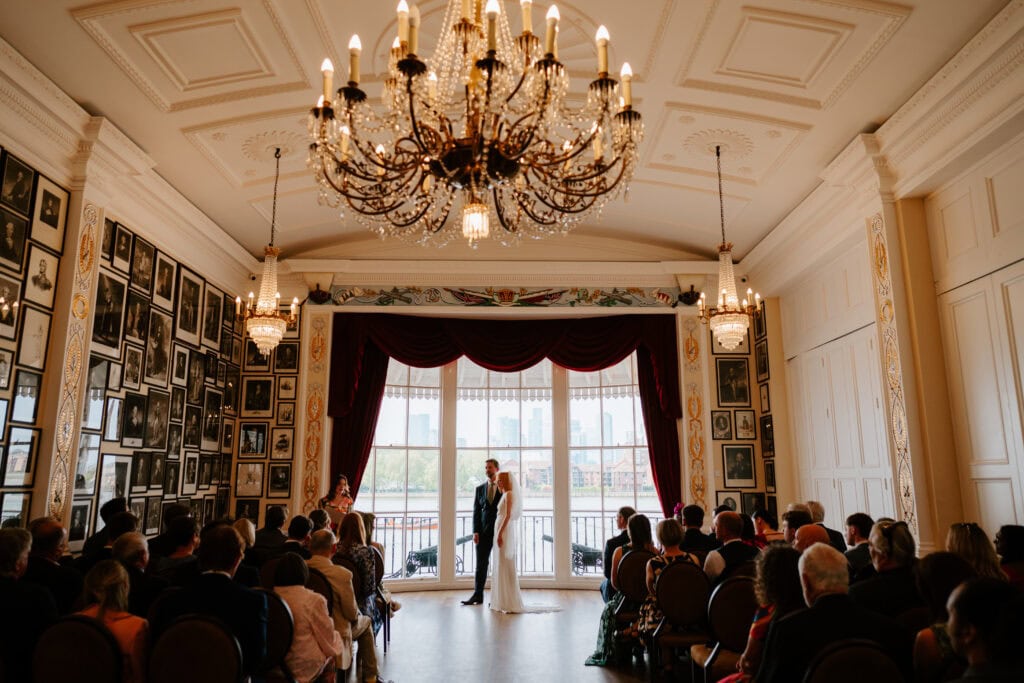 Elegant wedding ceremony in ornate venue with chandeliers.