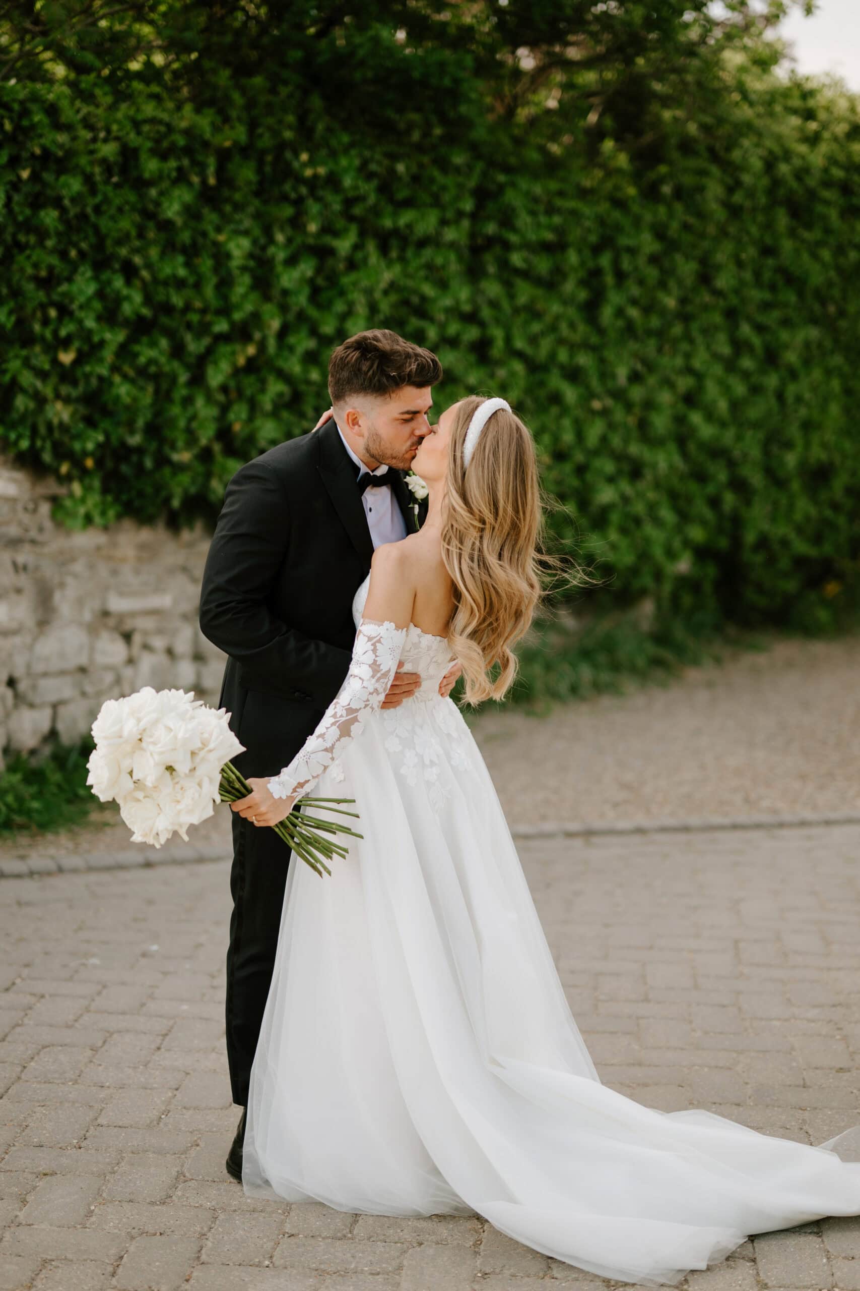 Bride and groom kissing outdoors on wedding day.