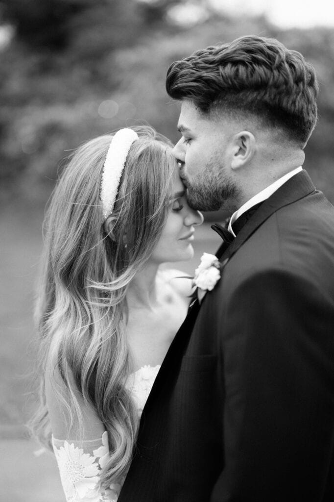Bride and groom sharing tender forehead kiss