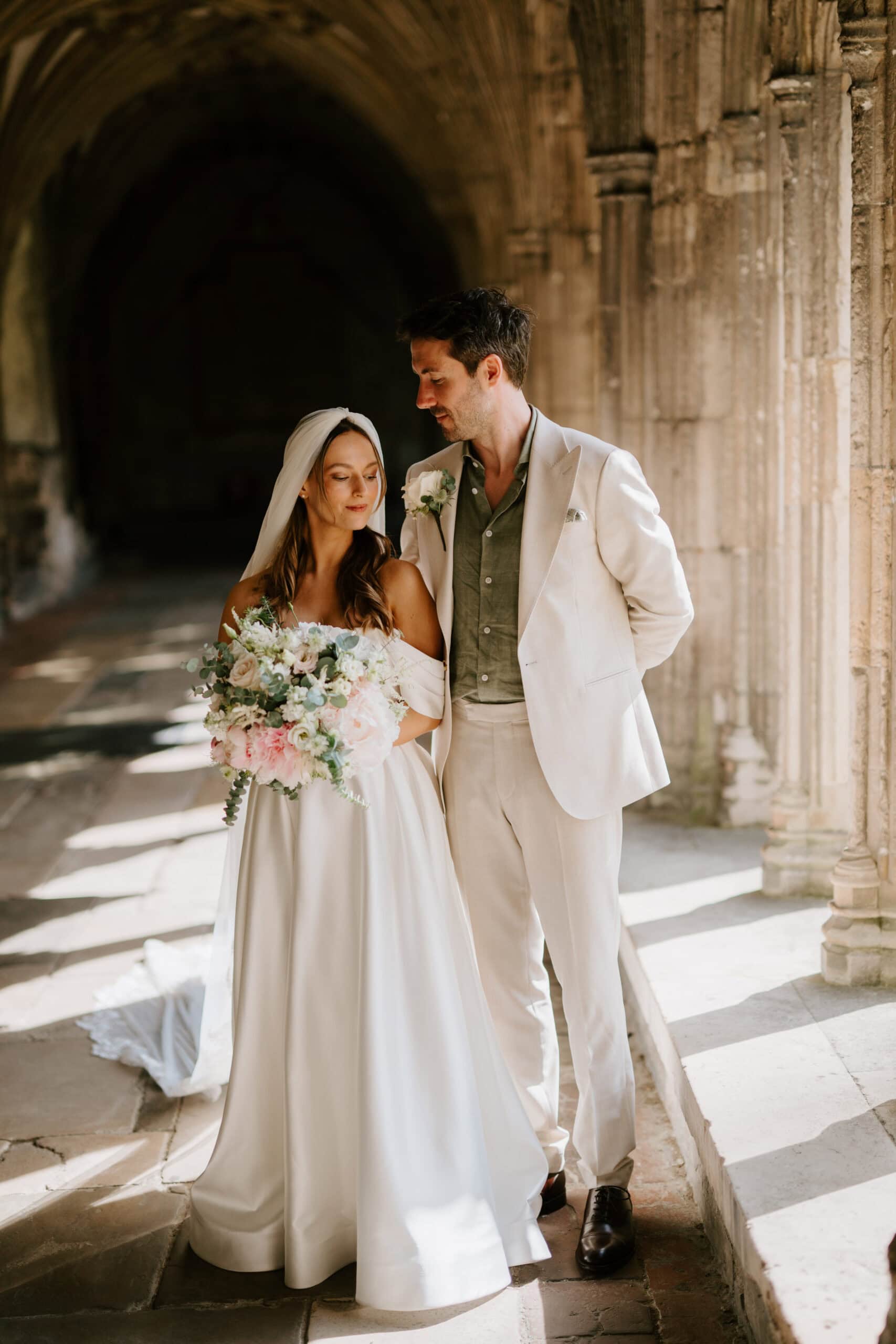 Bride and groom in sunlit historic canterbury catherdral.