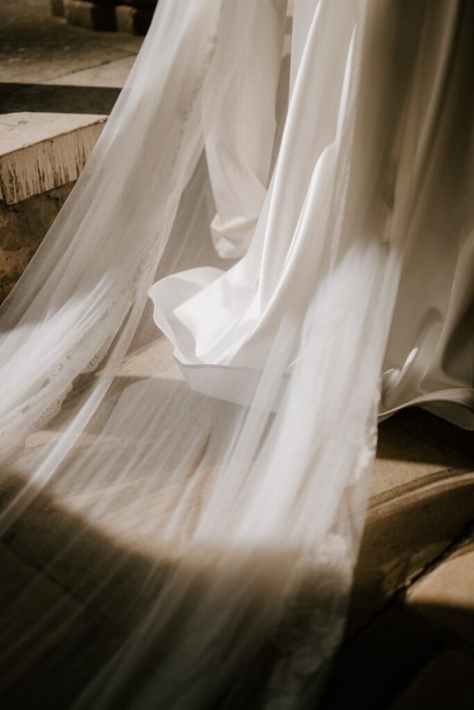 Elegant flowing wedding dress on stone steps.