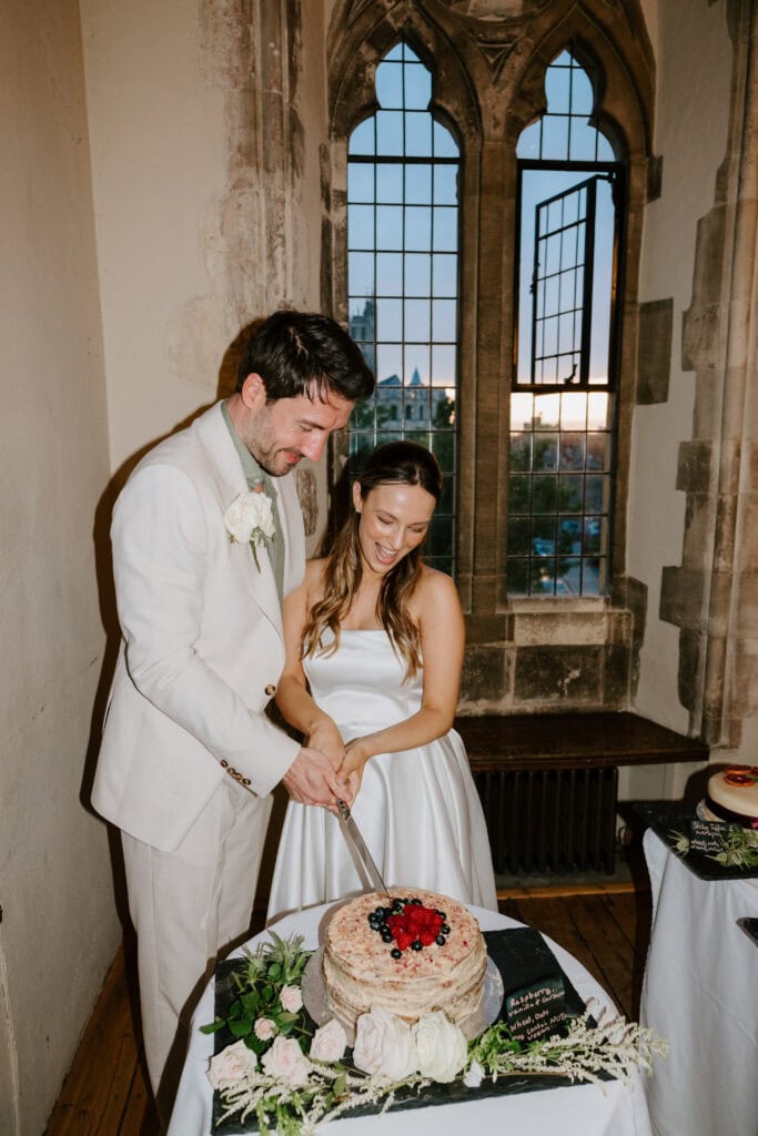Couple cutting wedding cake in historic venue.