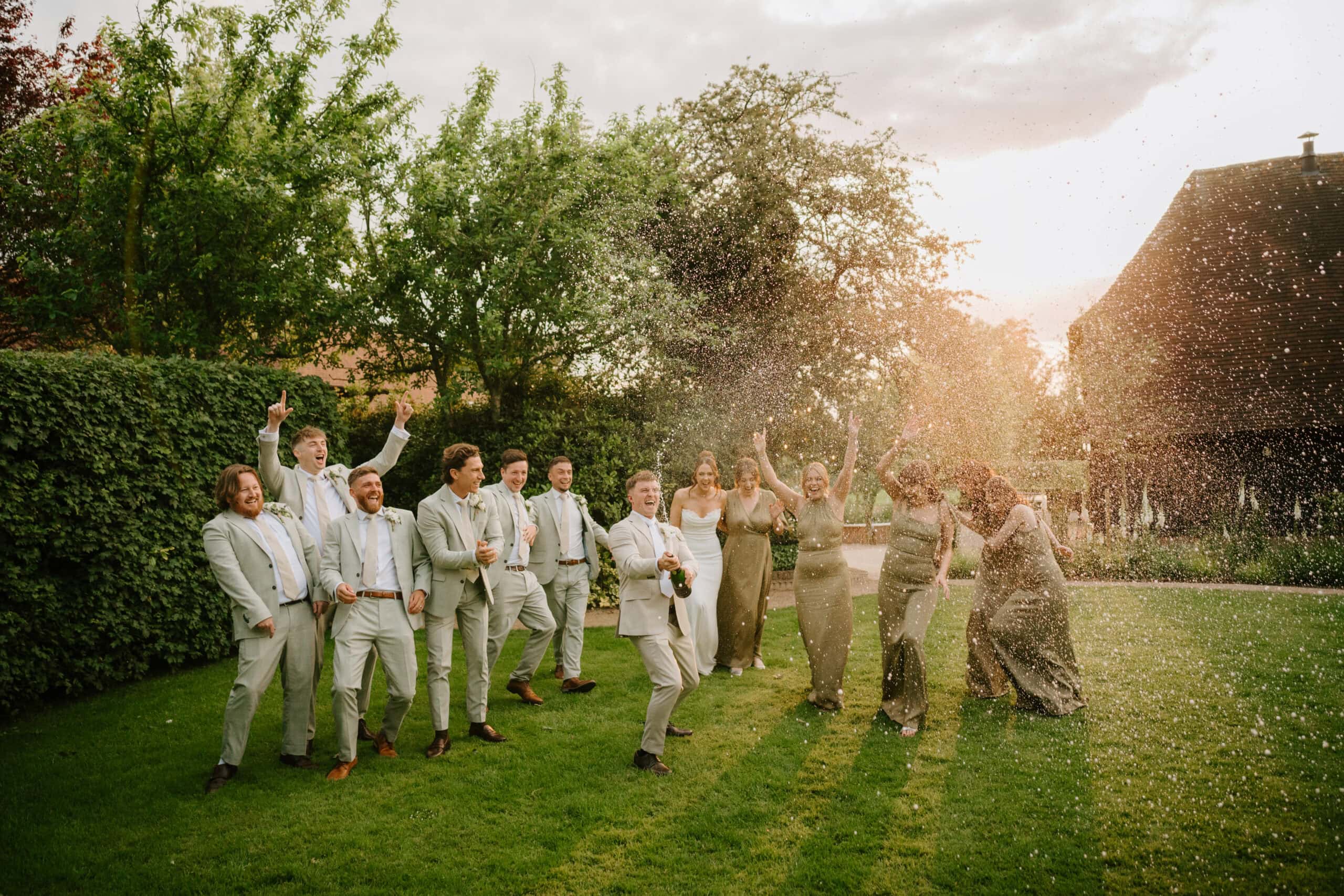 Group celebrating with champagne outdoors at sunset at the old kent barn