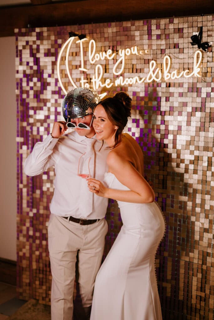 Couple posing with disco theme and romantic sign.