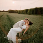 Couple on their wedding day kissing in field at sunset at the old kent barn