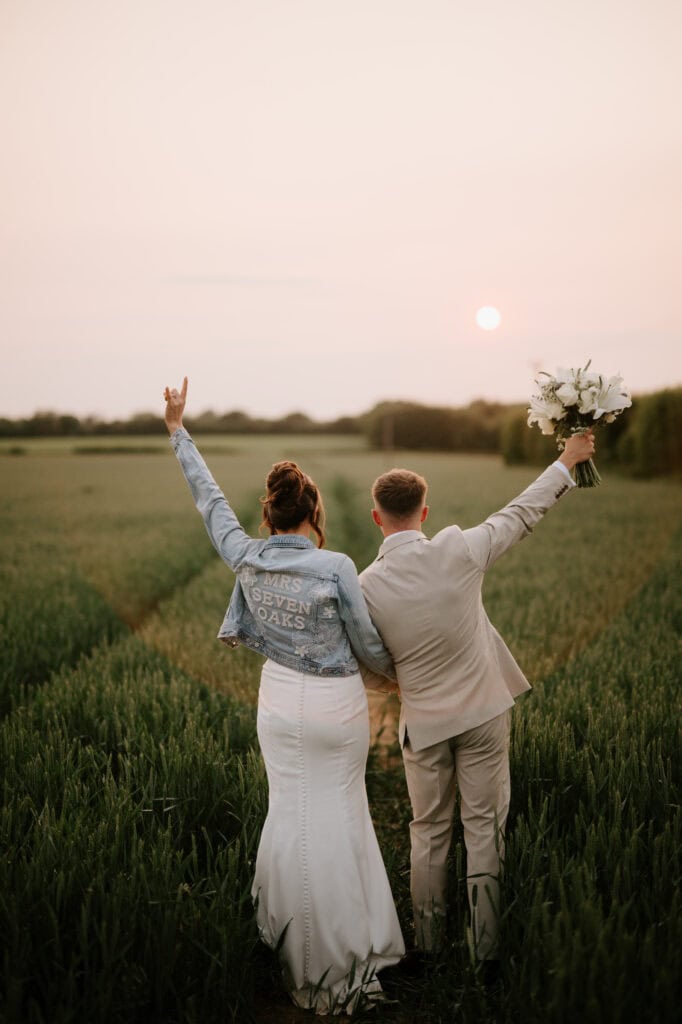 Bride and groom celebrate in sunset field
