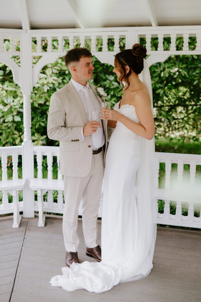 Bride and groom under gazebo holding glasses