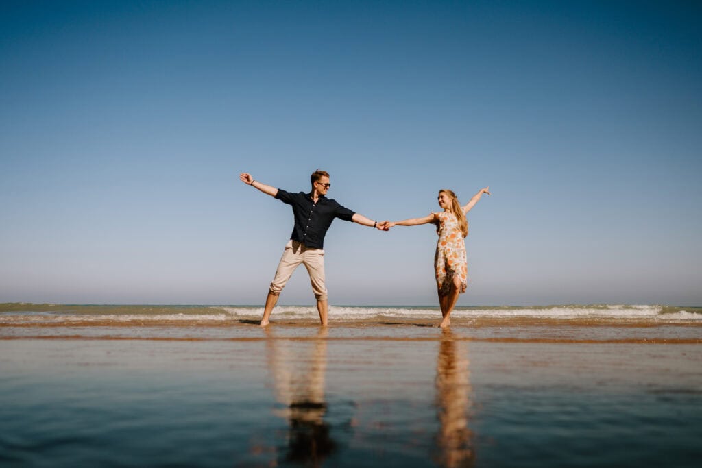 Couple dancing joyfully on the beach.