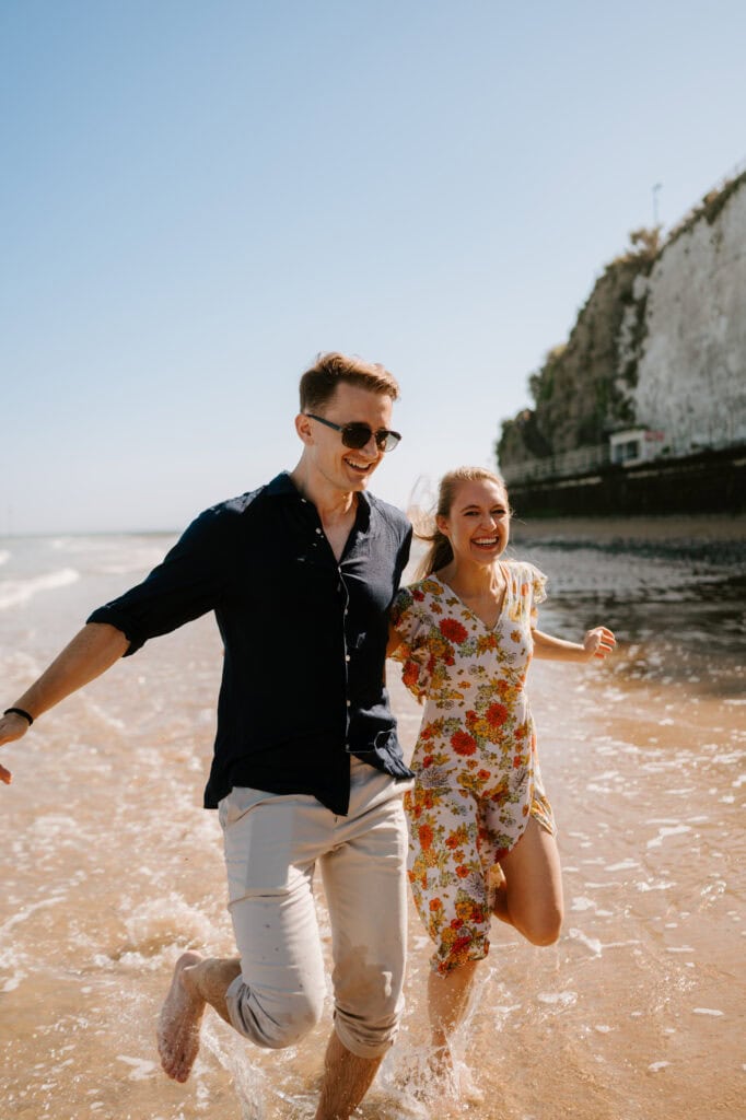 Couple running joyfully through seaside waves