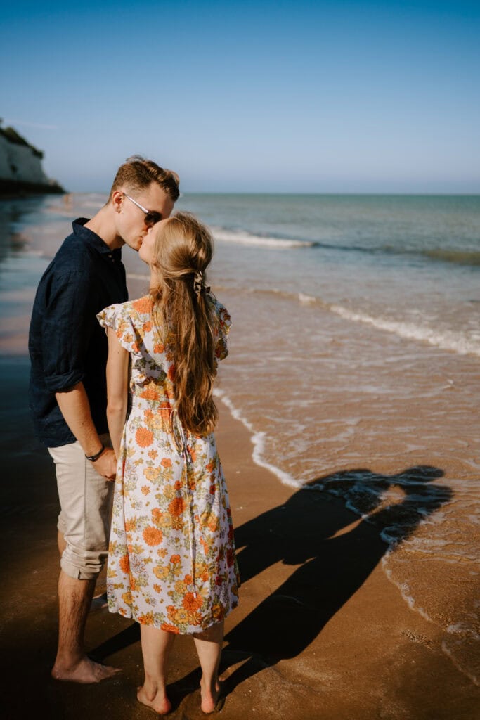 Couple kissing on sandy beach under clear sky