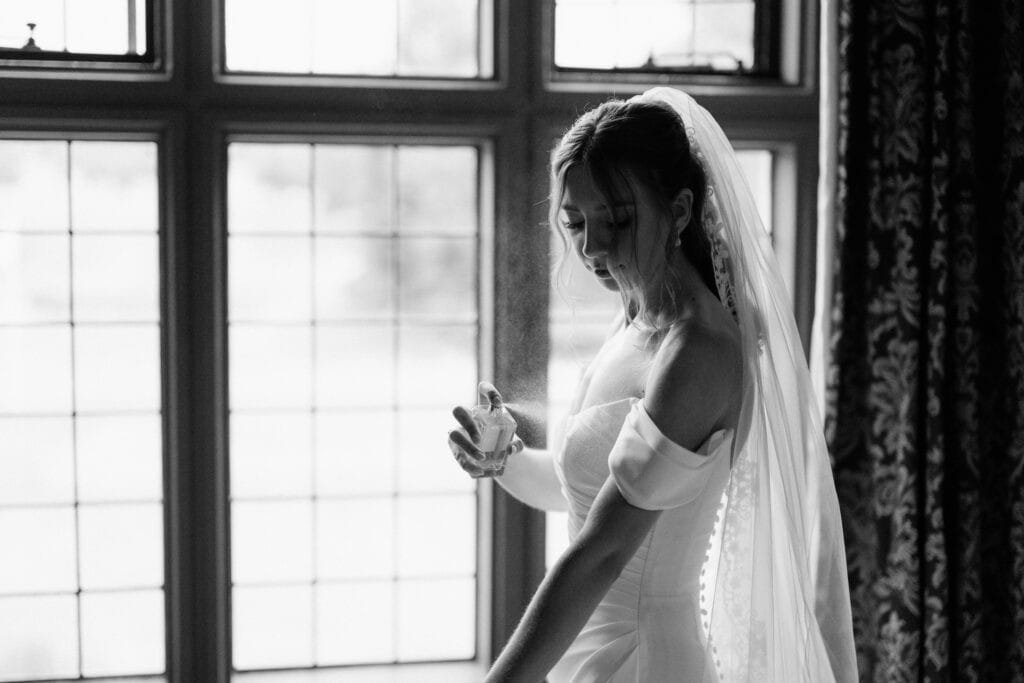 A bride is standing by the window in her wedding dress.