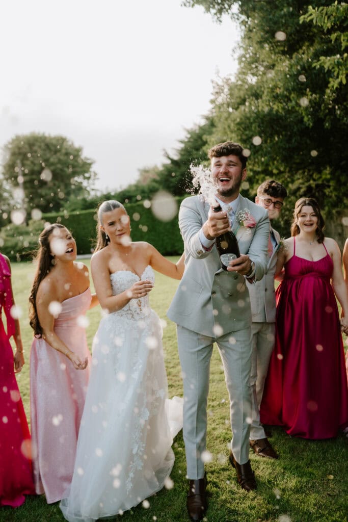 Wedding party celebrating with champagne outdoors.