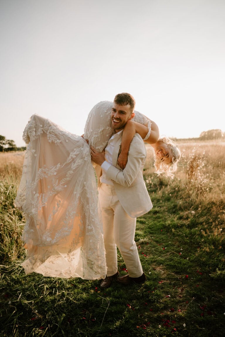 Groom carrying bride in a sunny field