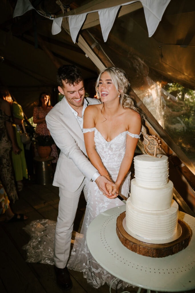 Bride and groom cutting wedding cake together.