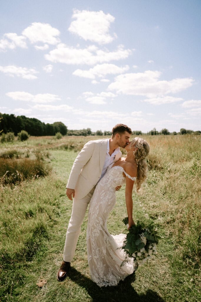 Bride and groom kissing in a meadow at wilderness weddings kent