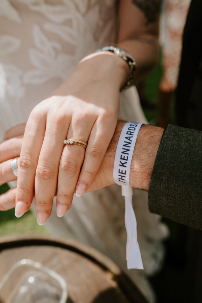 Couple holding hands with wedding rings visible.