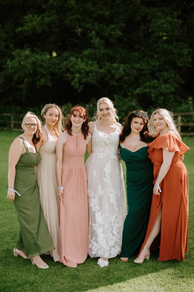 Six women in colourful dresses on grass
