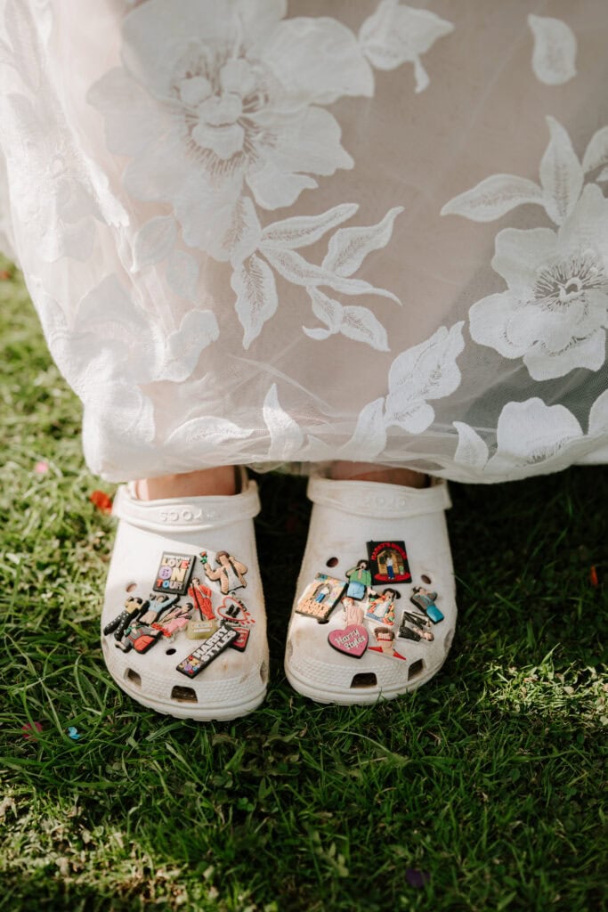 White Crocs with colourful pins on grass.
