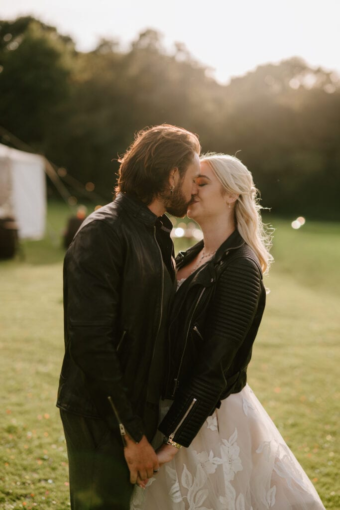 Couple kissing outdoors in sunshine with jackets.