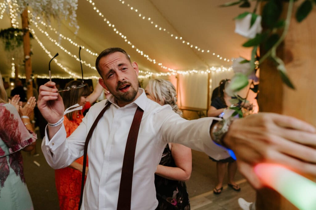 Smiling man dancing at festive party under lights.