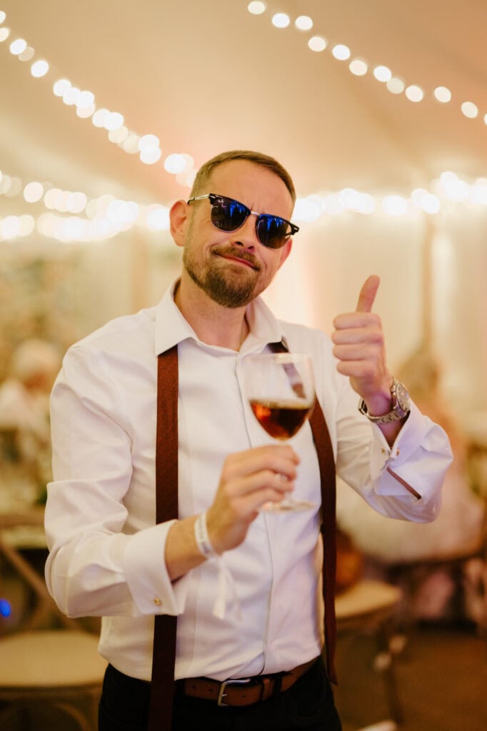 Man with sunglasses toasting at party.