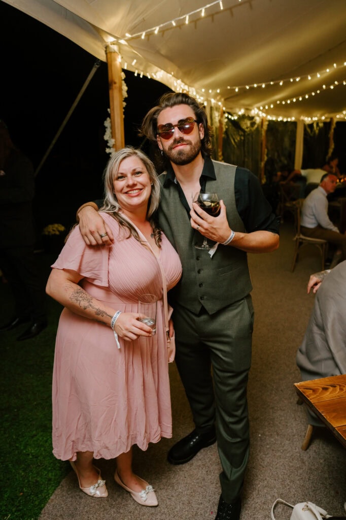 Smiling pair at an evening party, holding drinks.