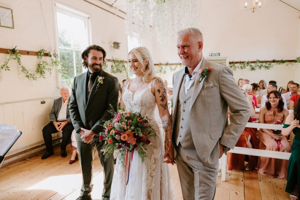 Bride walking down the aisle with father and groom.