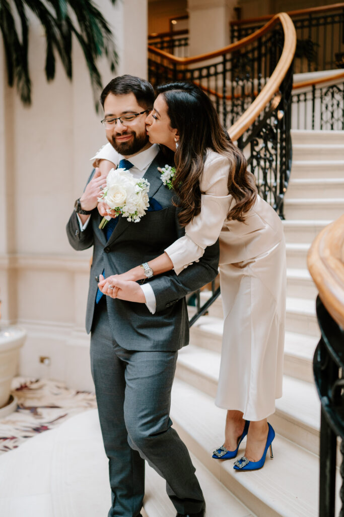 Couple embraces on staircase with bouquet.