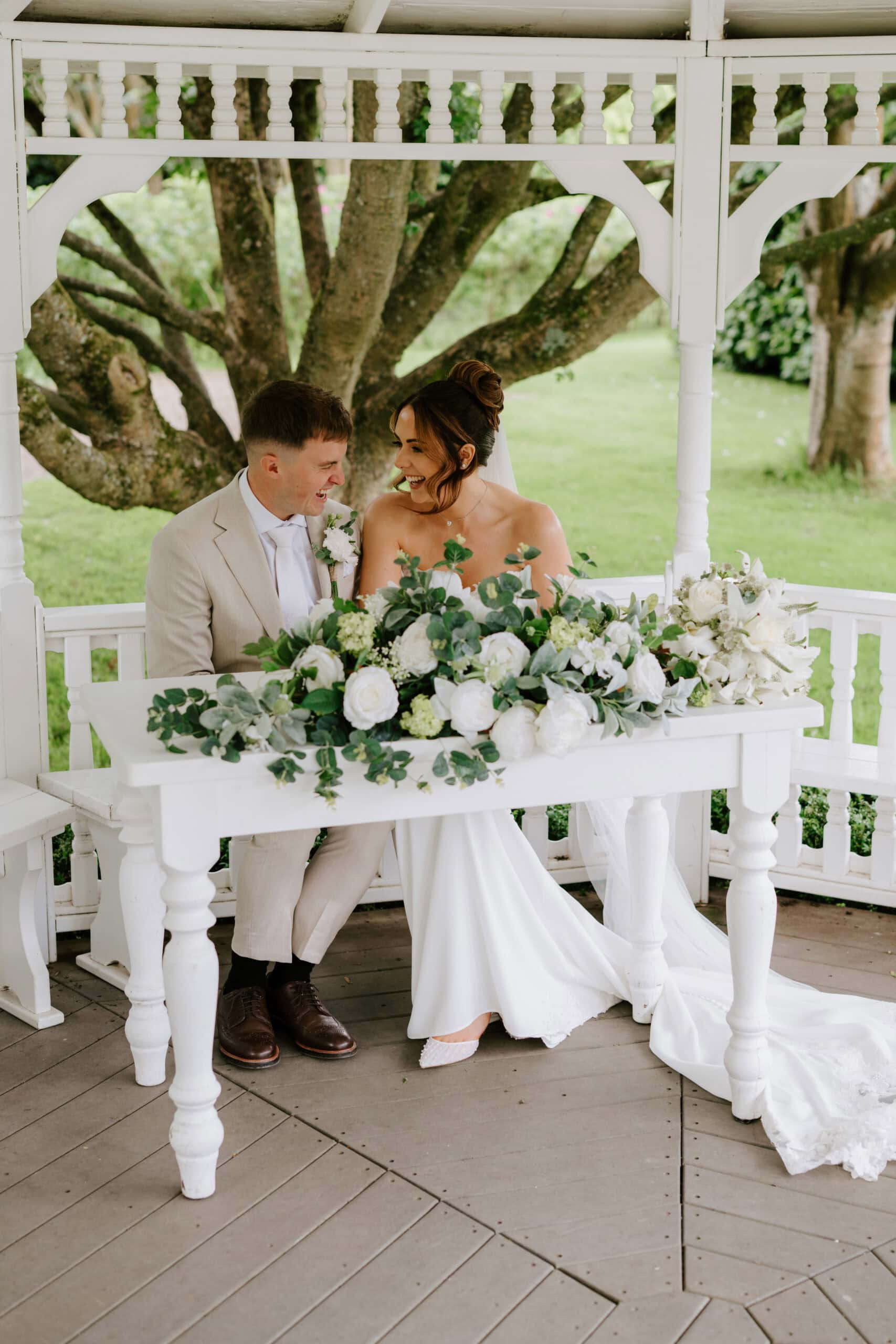 Smiling couple at wedding ceremony signing table.