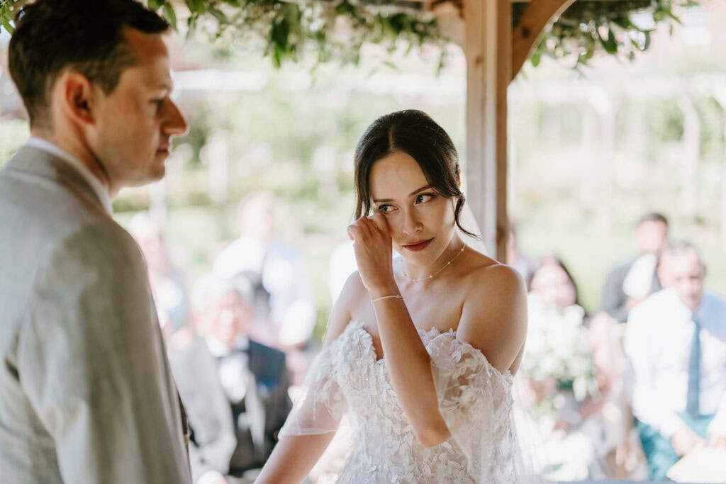 Bride wipes tear during wedding ceremony