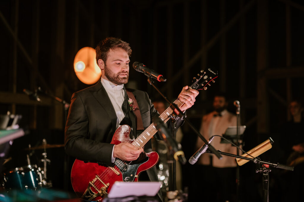 Man playing guitar on stage with microphone.