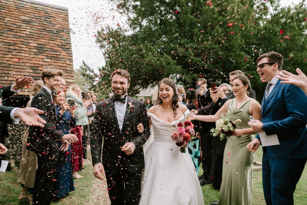 Bride and groom walking through confetti at wedding.