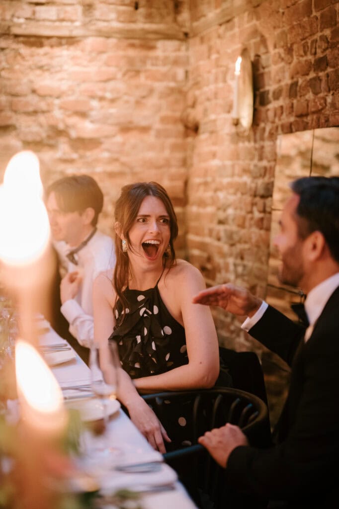 Guests laughing at a candlelit dinner.