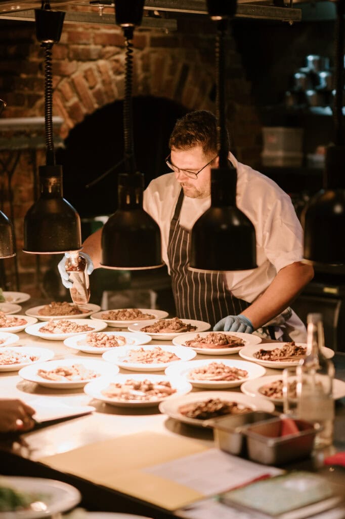 Chef plating multiple gourmet dishes in a kitchen